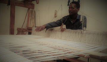 Ethiopian shemane weaver at a hand loom making traditional cotton textile