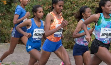 A group of Ethiopian women runners with race bibs reading Abebech, Yebrgual and Merima run on a road lined with autumn bushes at the 2017 Frankfurt Marathon