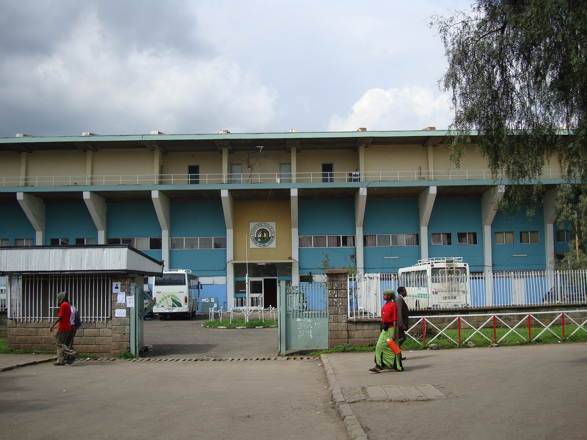Front of Addis Ababa Stadium with blue and cream stands, a gate and two buses parked inside, Addis Ababa, August 2008