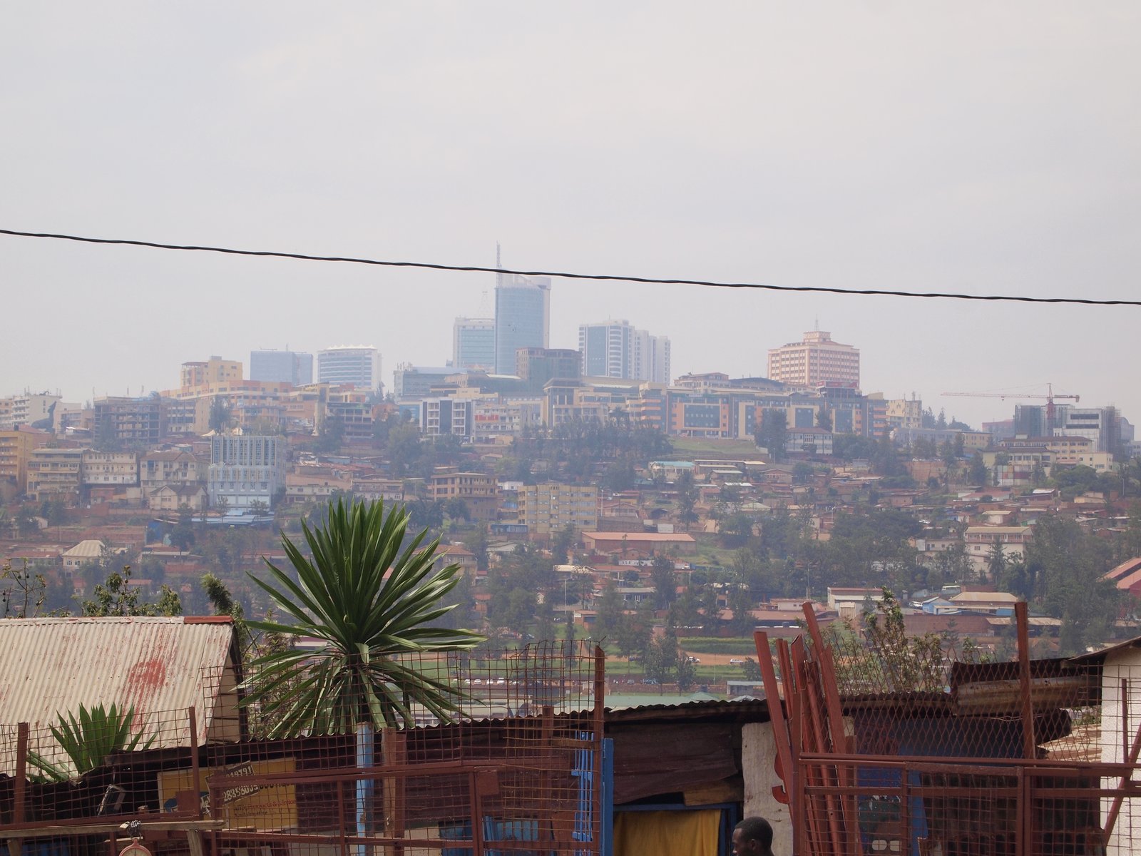 Office towers and hillside houses on the skyline of Kigali, Rwanda, seen under a grey sky in March 2018
