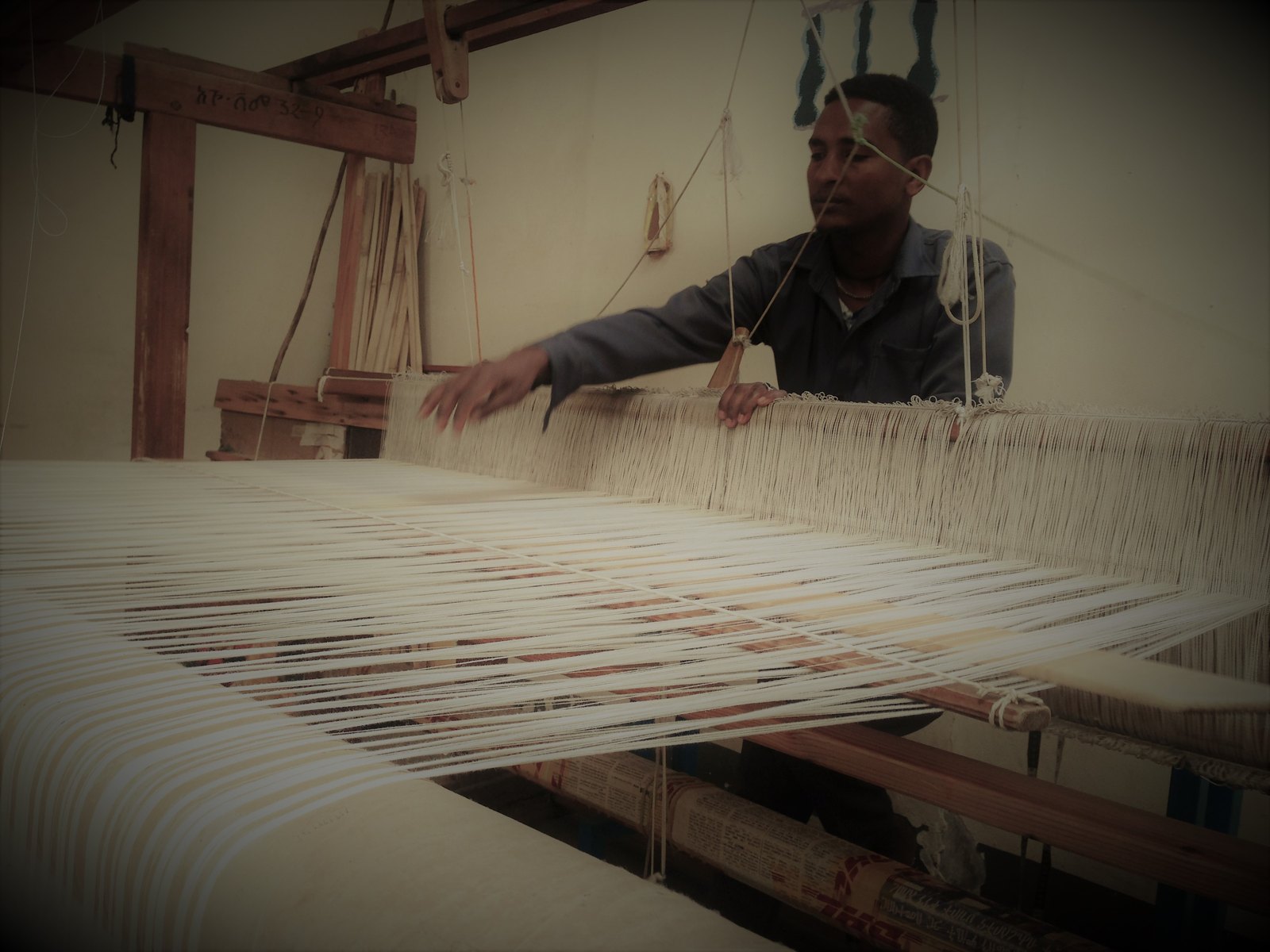 A weaver works at a hand loom with white cotton threads at the Sabahar textile workshop in Addis Ababa, Ethiopia, 2017